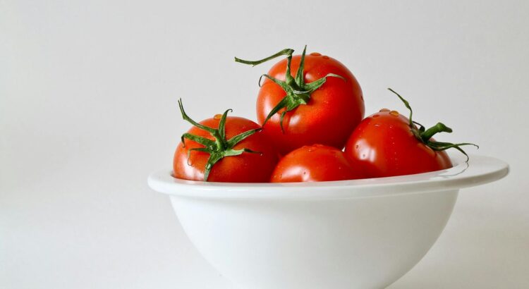 Vibrant red tomatoes in a white bowl, emphasizing freshness and simplicity.