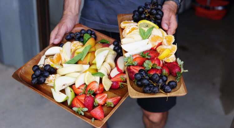 a person holding two trays of fruit
